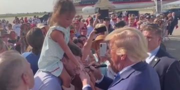 Former President Donald Trump signs a young girl's hand in Louisiana.