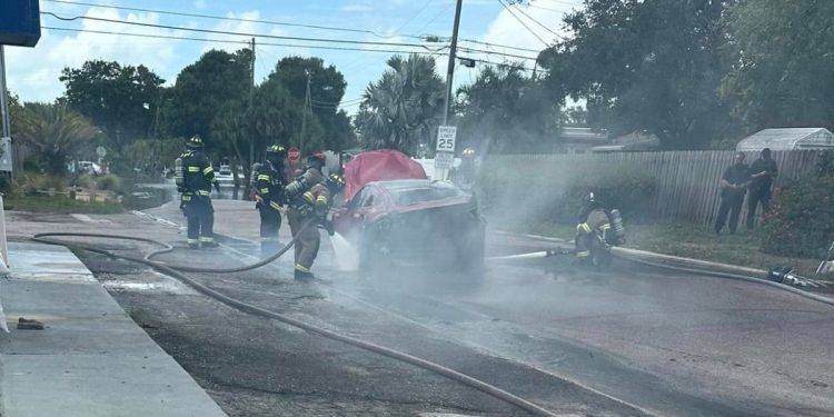 firefighters working to extinguish the flames in a burning Tesla