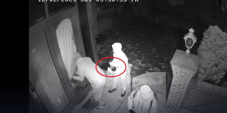 A still from a surveillance video shows a gang breaking into a home -- with one of the men holding a jammer.