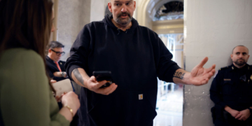 WASHINGTON, DC - FEBRUARY 12: Sen. John Fetterman (D-PA) uses a speech-to-text app on his iPhone to better understand a reporter's questions in between votes at the U.S. Capitol on February 12, 2024 in Washington, DC. Following a series of evening votes, the Senate will stay in session all night with the goal of passing national security legislation that would send $95 billion in military aid to Ukraine, Israel and Taiwan. (Photo by Chip Somodevilla/Getty Images)