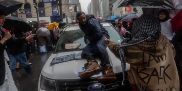 A pro-Hamas demonstrator sits on the hood of a New York City police vehicle that's surrounded by Hamas sympathizers Saturday in Manhattan.